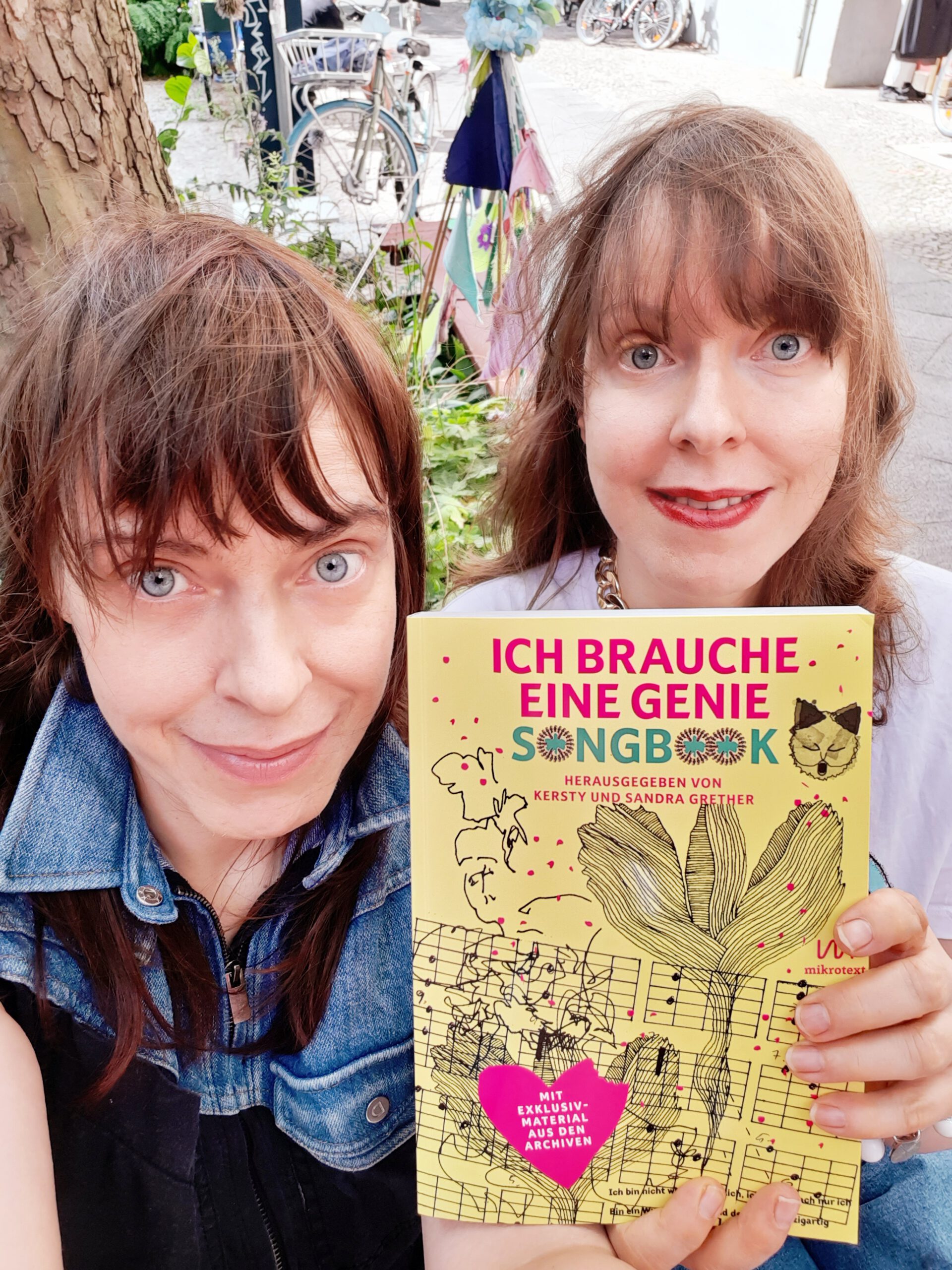 Kersty und Sandra Grether halten ihr gelbes Songbook in die Kamera